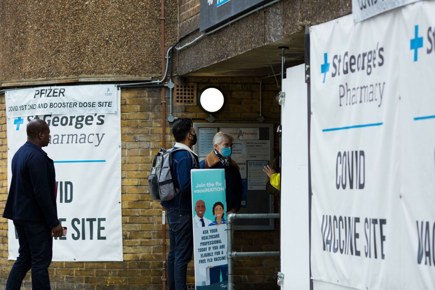 anners of a Covid vaccine site are seen displayed outside a pharmacy in London.